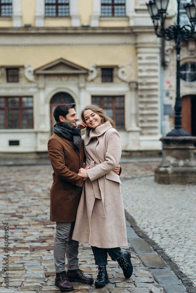 Beautiful romantic lovely couple on the central square of the cloudy Europe city