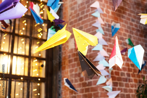 Festive decoration of the room, colorful paper planes. Glowing lights on large Windows. Children's holiday.