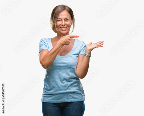 Middle age senior hispanic woman over isolated background amazed and smiling to the camera while presenting with hand and pointing with finger.