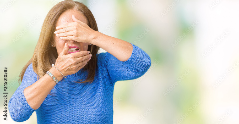 Obraz premium Middle age beautiful woman wearing winter sweater over isolated background Covering eyes and mouth with hands, surprised and shocked. Hiding emotion