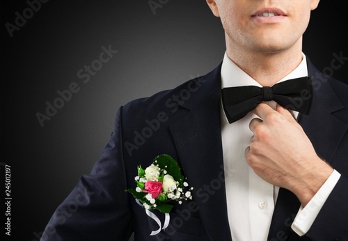 Male groom in wedding suit with bow tie on black