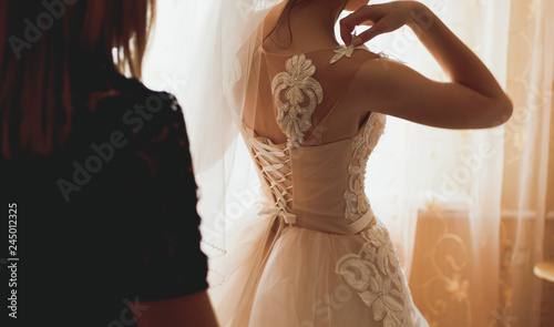 Bridal morning details. Beautiful girl is wearing her elegant white lace and satin dress. Happy wedding day picture.