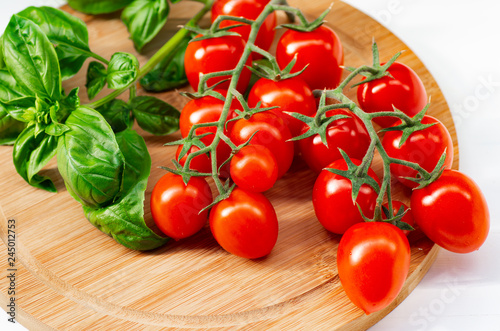 The branch of cherry tomatoes on a wooden background.