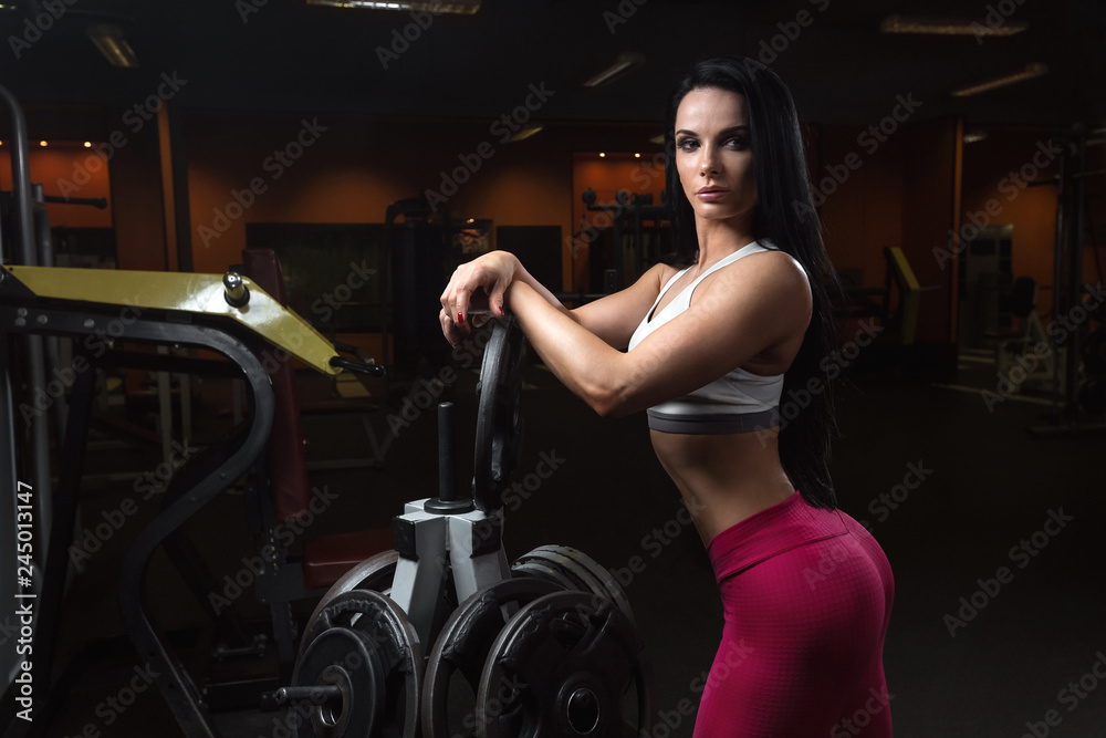 Fototapeta premium Young woman athlete is resting and posing after exercises with weight plate
