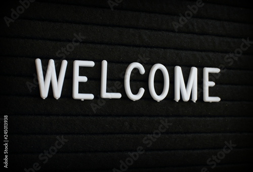 The word Welcome in white plastic letters on a black letter board 