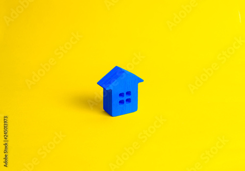 A small wooden house stands on a yellow background. The concept of buying and selling real estate, renting. Search for a house. Affordable housing, credit and loans. Investments in business