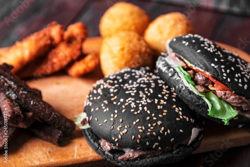 Black hamburger, fast food on wooden background