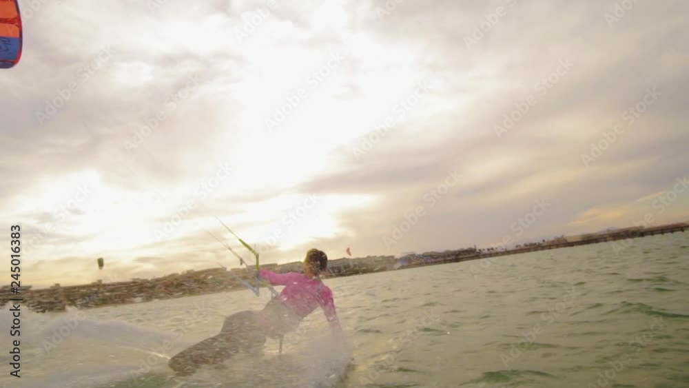 Beautiful young woman kiteboarding at sunset in slow motion, active lifestyle extreme sport Beautiful young woman kiteboarding at sunset in slow motion, active lifestyle extreme sport
