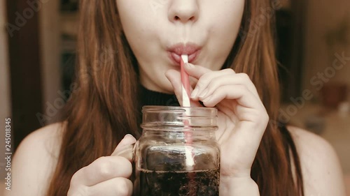 A young girl drinks a fizzy drink through a straw. Face close up. HD