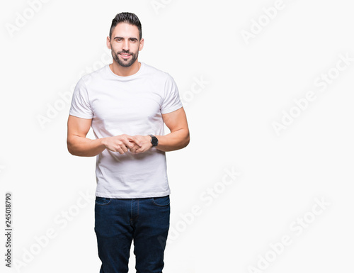 Handsome man wearing white t-shirt over white isolated background Hands together and fingers crossed smiling relaxed and cheerful. Success and optimistic © Krakenimages.com