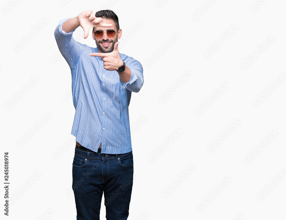 Fototapeta premium Young handsome man wearing sunglasses over isolated background smiling making frame with hands and fingers with happy face. Creativity and photography concept.