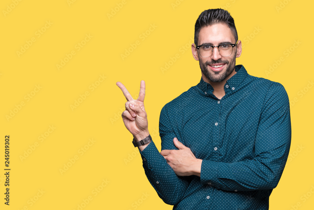 Young handsome business man wearing glasses over isolated background smiling with happy face winking at the camera doing victory sign. Number two.