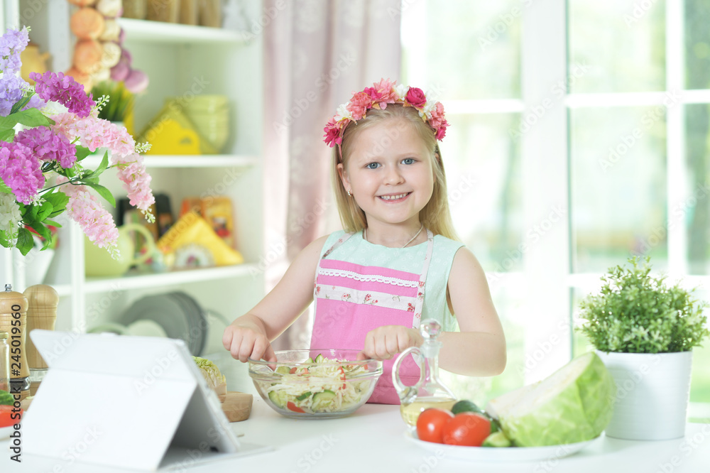 little girl preparing salad on kitchen table little girl preparing salad on kitchen table