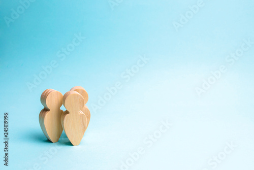 three people stand together and talk. Communication, meeting place. Two wooden figures of people conduct a conversation on a blue background. Place for text. Minimalism. Selective focus photo