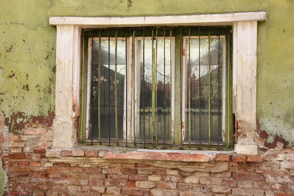 window with bars on a house in ruins  near  a bench in Bistrita,Romania