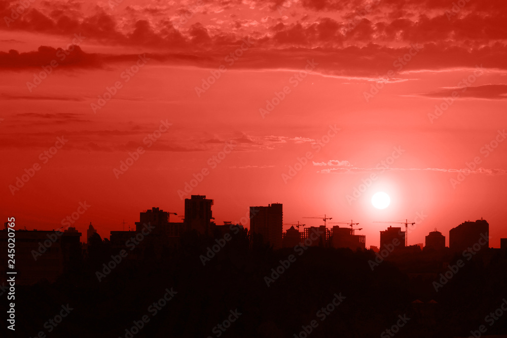 Dramatic sunset over the evening city of Kyiv toned in coral color which is the main trend in the year 2019. Beautiful view on contrast horizon.