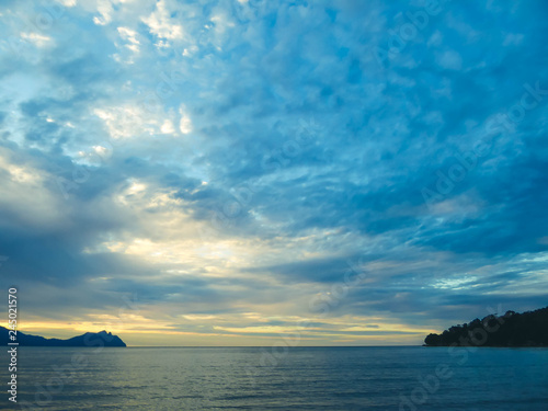 Beautiful formation of clouds over the sea in Bako National Park, Borneo, Malaysia during the sunset. Blue and yellow sky. Two islands visible on both sides of the picture. Overcast.  © Chris