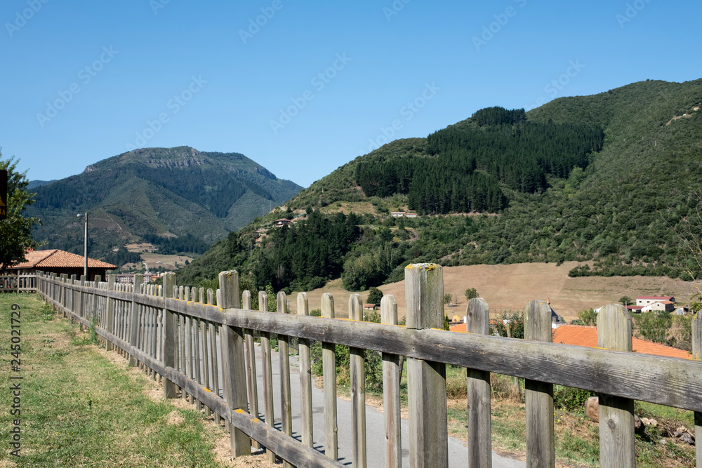 wooden fence in a meadow with the mountains of asturias in the background on a sunny day