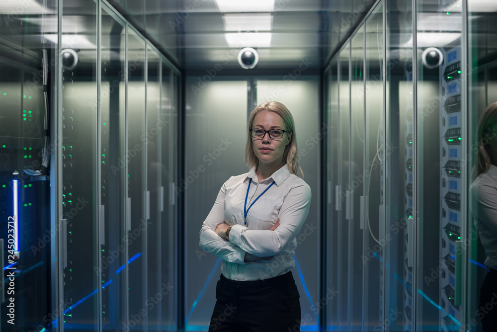 Φωτογραφία Adult IT worker in white shirt standing among server racks in data center smilin