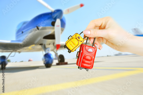 Miniature baggage in female hands on blurred background with plane airscrew.Travel and luggage concept.