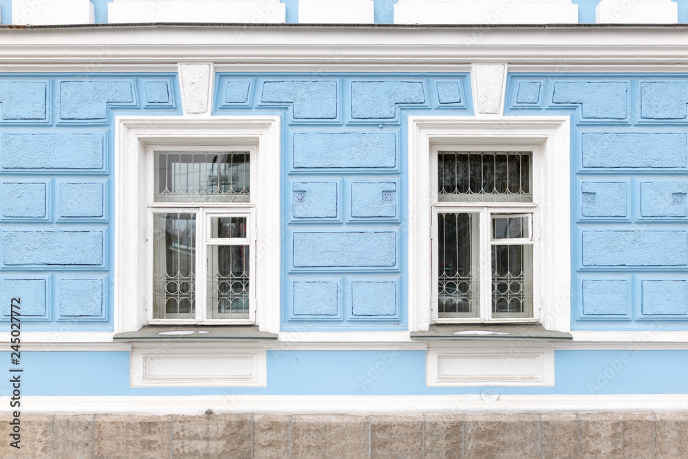 Two windows of an old 19th century mansion with blue walls