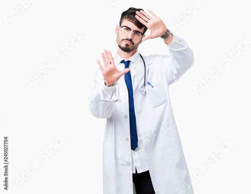 Young doctor man wearing hospital coat over isolated background Smiling doing frame using hands palms and fingers, camera perspective