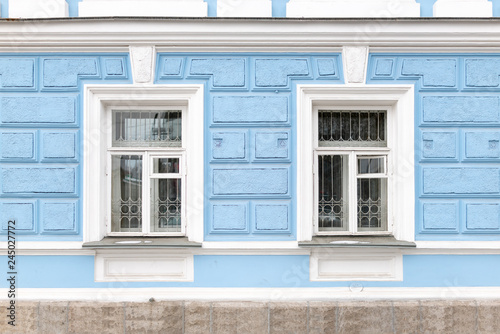 Two windows of an old 19th century mansion with blue walls