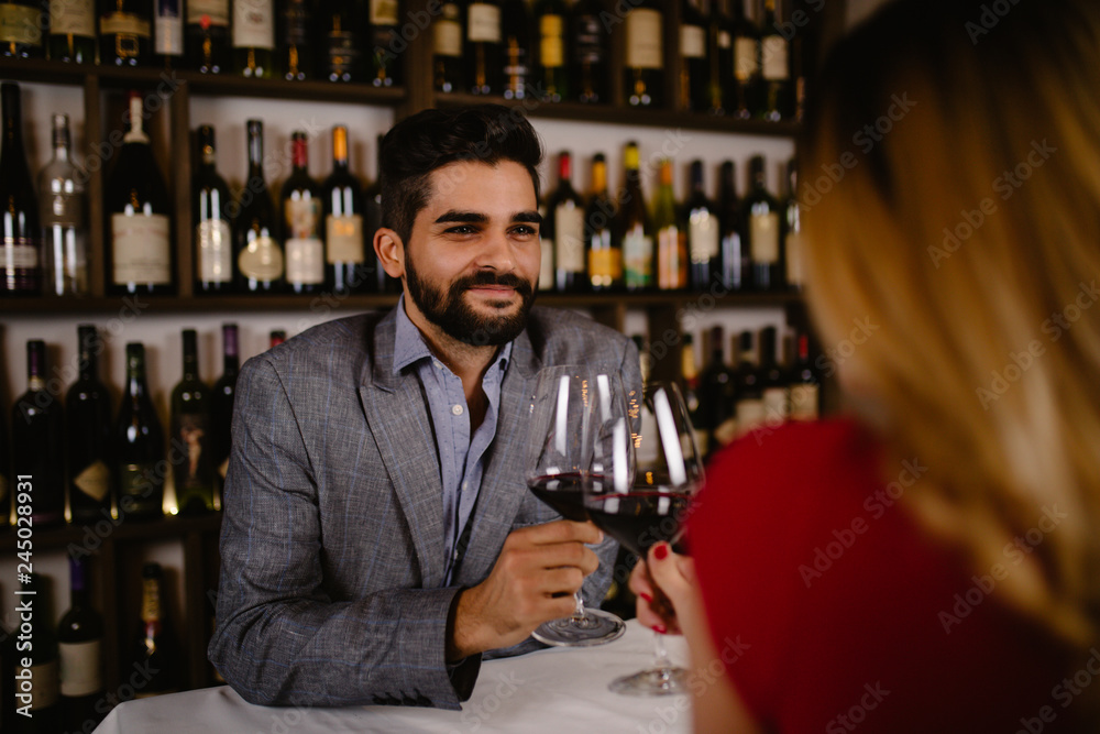 Attractive young couple clinking by wine glasses in restaurant during date.