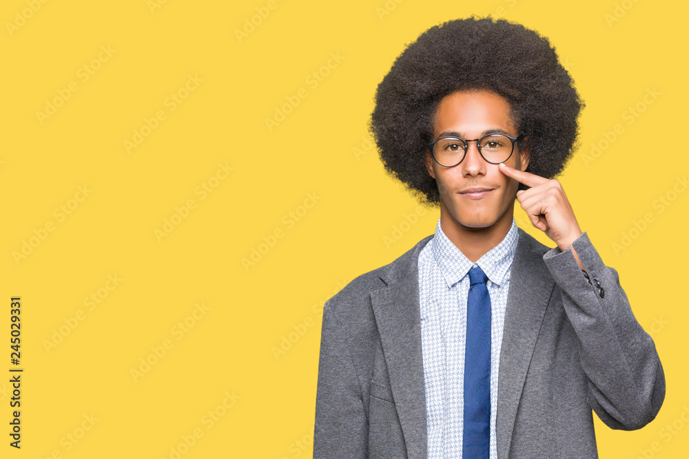 Young african american business man with afro hair wearing glasses Pointing with hand finger to face and nose, smiling cheerful Young african american business man with afro hair wearing glasses Pointing with hand finger to face and nose, smiling cheerful
