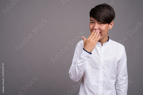 Young Asian teenage boy against gray background