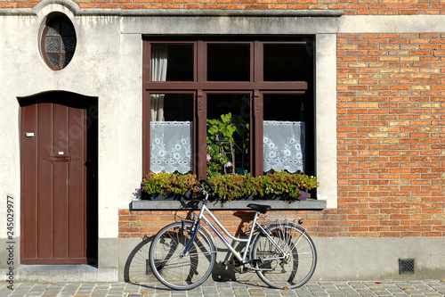bike  near the wall of a brick house, next to the window and the door
