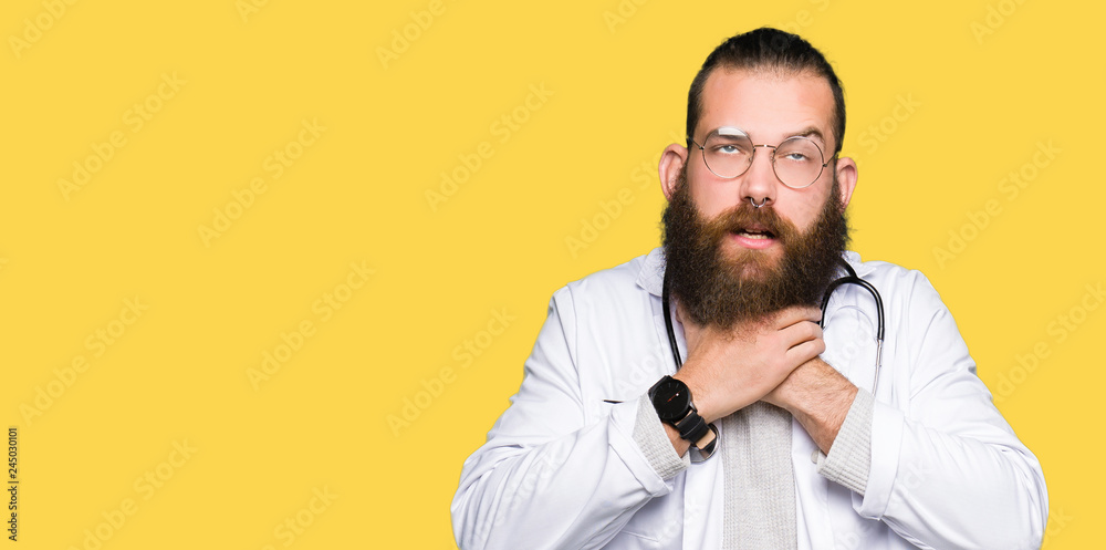 Young blond doctor man with beard wearing medical coat shouting and suffocate because painful strangle. Health problem. Asphyxiate and suicide concept. Young blond doctor man with beard wearing medical coat shouting and suffocate because painful strangle. Health problem. Asphyxiate and suicide concept.