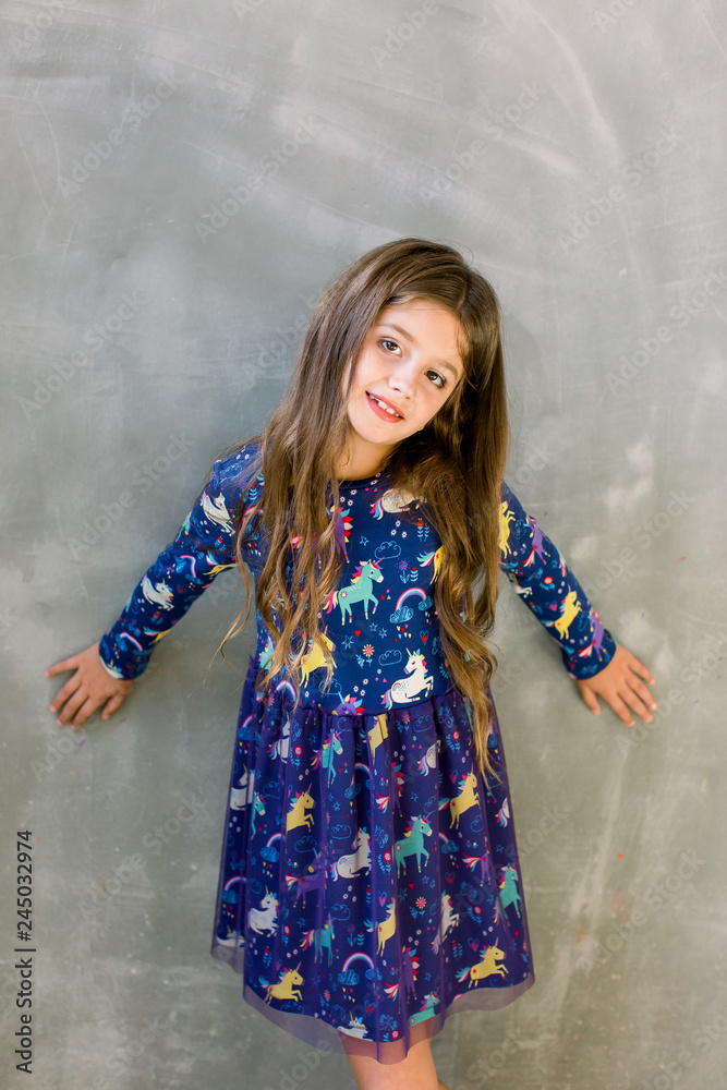 Small girl child model in beautiful dress. Childhood, look, happiness,  hairstyle. Kid fashion, hairdresser, birthday. Little girl with long hair  on grey background. Stock Photo | Adobe Stock