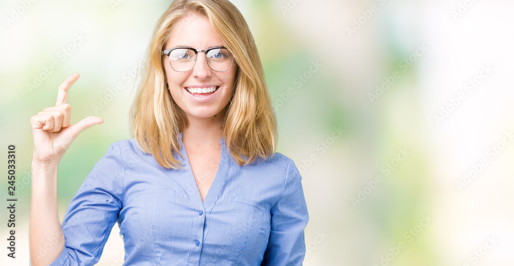 Fototapeta premium Beautiful young business woman over isolated background smiling and confident gesturing with hand doing size sign with fingers while looking and the camera. Measure concept.