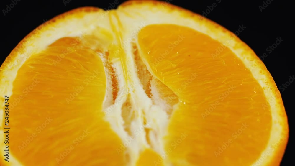 Close-up of an orange cut in half rotated on a black background. Fresh slice of orange on black background. Macro shot orange pulp fresh slice orange. Close-up of an orange cut in half rotated on a black background. Fresh slice of orange on black background. Macro shot orange pulp fresh slice orange.