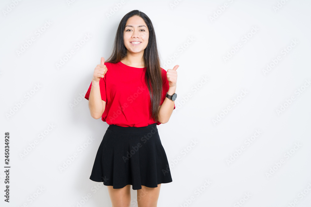 Beautiful brunette woman wearing red t-shirt and skirt over isolated background success sign doing positive gesture with hand, thumbs up smiling and happy. Looking at the camera