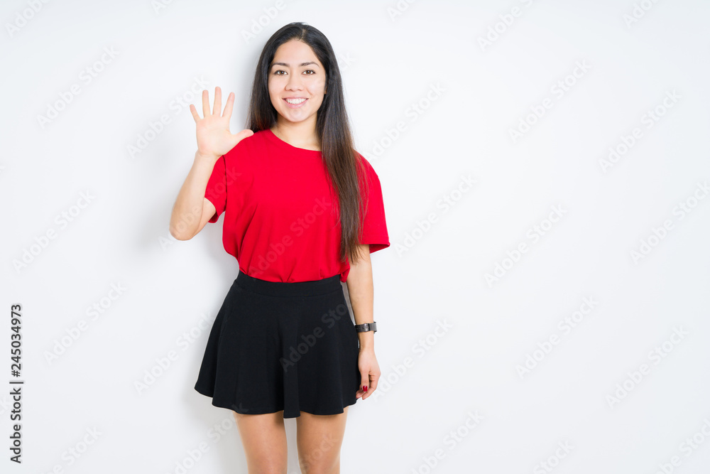 Beautiful brunette woman wearing red t-shirt and skirt over isolated background showing and pointing up with fingers number five while smiling confident and happy. Beautiful brunette woman wearing red t-shirt and skirt over isolated background showing and pointing up with fingers number five while smiling confident and happy.