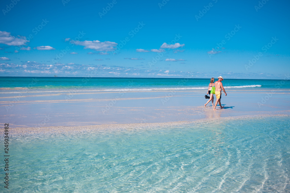 Couple in the distance, man and a woman are on the beautiful beach.