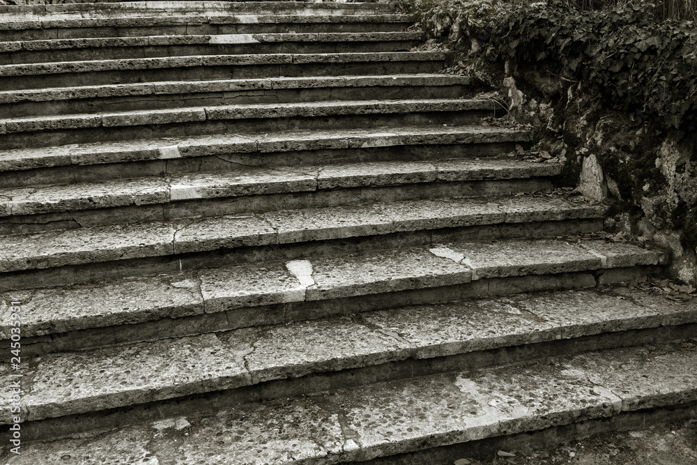 An old open outer stone staircase. Stone, cement steps of the old staircase with traces of weathering and destruction. An ancient stone staircase, ancient broken worn steps. Selective focus An old open outer stone staircase. Stone, cement steps of the old staircase with traces of weathering and destruction. An ancient stone staircase, ancient broken worn steps. Selective focus