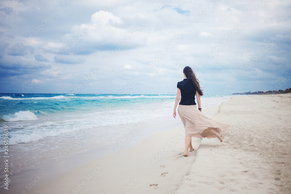 young woman in a long skirt walking on the ocean. young woman in a long skirt walking on the ocean.
