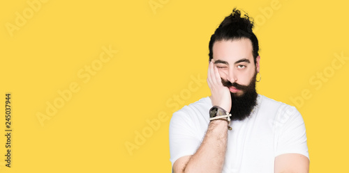 Young hipster man with long hair and beard wearing casual white t-shirt thinking looking tired and bored with depression problems with crossed arms. photo