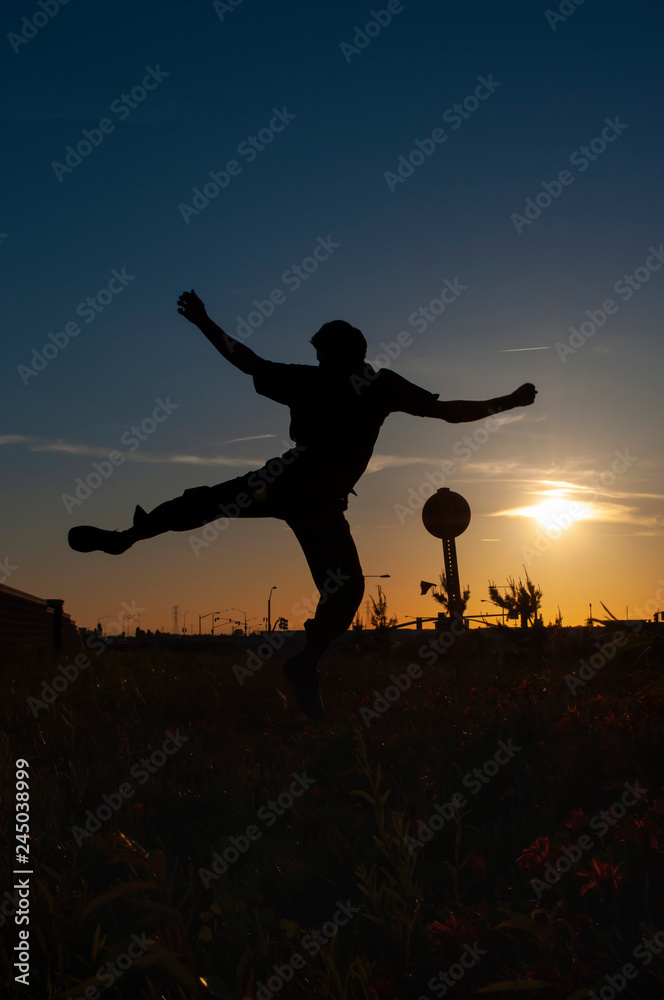 silhouette of a man jumping on sunset background of blue sky
