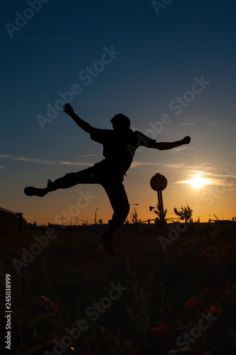 silhouette of a man jumping on sunset background of blue sky
