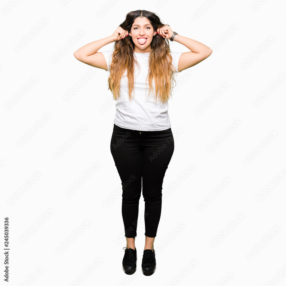 Fototapeta premium Young beautiful woman wearing casual white t-shirt Smiling pulling ears with fingers, funny gesture. Audition problem