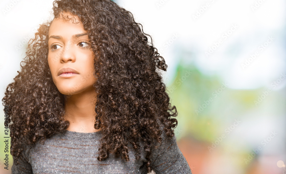 Young beautiful woman with curly hair wearing grey sweater with hand on stomach because indigestion, painful illness feeling unwell. Ache concept. Young beautiful woman with curly hair wearing grey sweater with hand on stomach because indigestion, painful illness feeling unwell. Ache concept.
