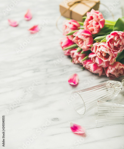 Valentines day holiday background. Bouquet of pink tulips and gift box with ribbon over white marble table background. Pink tulips and gift box with copy space. Lovers or Womens day greeting card photo