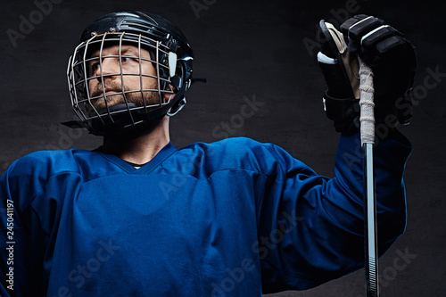 Photography Portrait of a bearded ice-hockey player in a blue sportswear with gaming stick