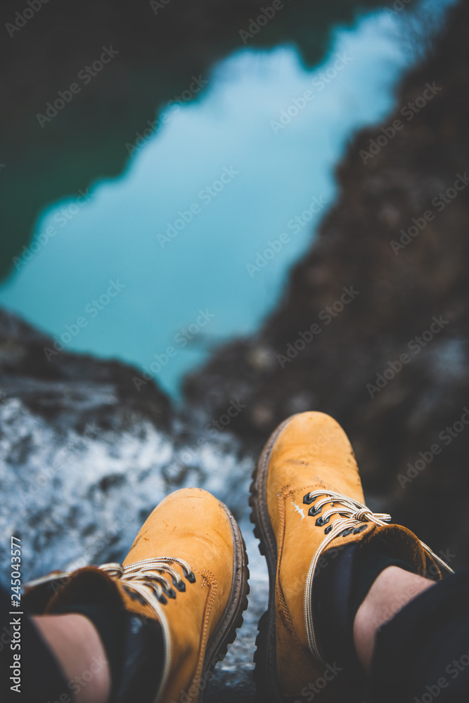 Feet of traveler or wild nature explorer in yellow dirty hiking