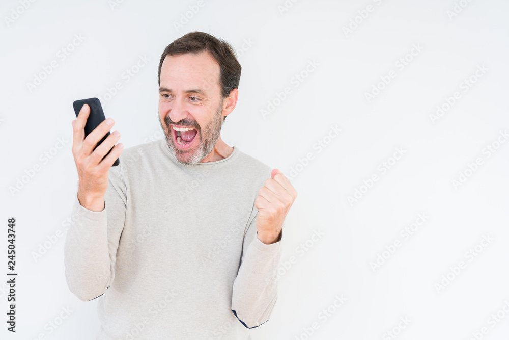 Senior man using smartphone over isolated background screaming proud and celebrating victory and success very excited, cheering emotion Senior man using smartphone over isolated background screaming proud and celebrating victory and success very excited, cheering emotion