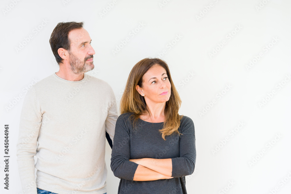 Beautiful middle age couple in love over isolated background smiling looking to the side with arms crossed convinced and confident Beautiful middle age couple in love over isolated background smiling looking to the side with arms crossed convinced and confident